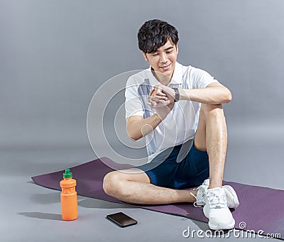 Young man runner doing stretching exercise and checking smart watch Stock Photo