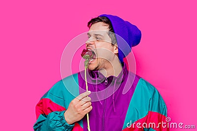 Young man in 90s clothes eating blossom peony flower Stock Photo