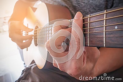Young man`s hands playing acoustic guitar.The guitar is a fretted musical instrument that usually has six strings.Practicing in Stock Photo