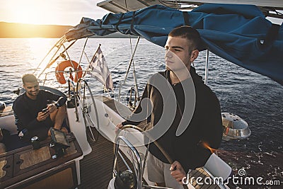 Young man at the sailboat helm Stock Photo