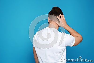 Young man scratching head on color background, space for text. Stock Photo