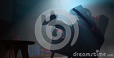 Young man seen from below jumping on a floating chair in his dark room using virtual reality goggles with blue light. 3D Stock Photo