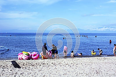 Young man sells and peddles ring lifebuoy on white sand beach Editorial Stock Photo