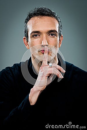 Young Man with Serious Expression Doing a Silent Sign Stock Photo