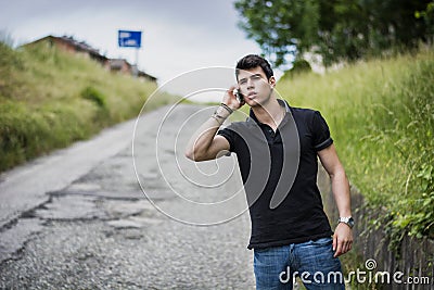 Young man on side of a road, calling and waiting for taxi Stock Photo