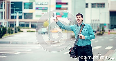 Young man on side of road hailing a taxi cab with a smart phone. Calling a taxi with a phone app concept Stock Photo