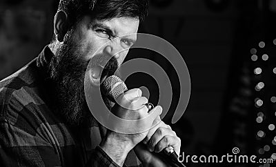 Young man singing with microphone. Hipster with beard Stock Photo