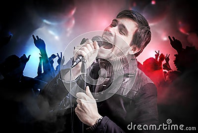 Young man is singing a somg in disco club. People are dancing in nightclub Stock Photo