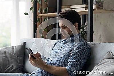 Young man sit on sofa with smart phone Stock Photo