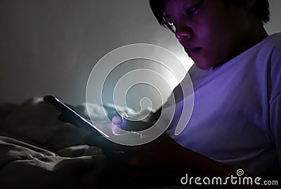 Young man sitting on the bed using smartphone at late night, Phone disease and Nomophobia. Healthy Concept Stock Photo