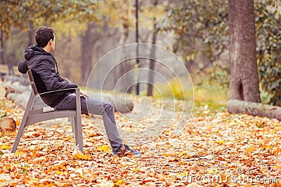 Young man sitting on a bench in a park Stock Photo