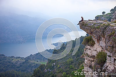 Young man sitting on edge of cliff Stock Photo