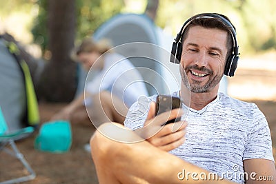 young man sitting in front tent listening to music Stock Photo