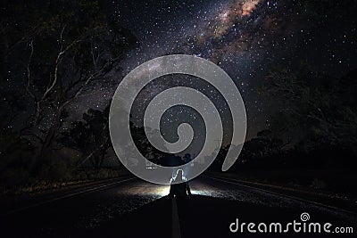 Young Man Sitting on Highway at Night Watching the Milkyway. Traveler and Astro Photography Concept Stock Photo