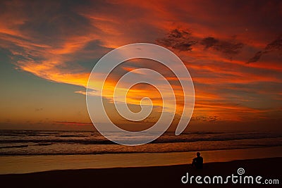 Young man sitting outdoors watching the sunset. Thinking and relaxing concept, Australia Stock Photo