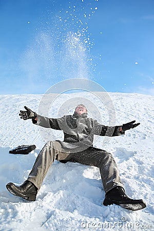 Young man sitting on snow and throw him upwards Stock Photo