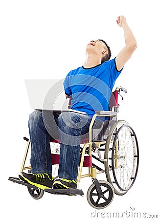 Young man sitting on a wheelchair and excited to raise arm Stock Photo