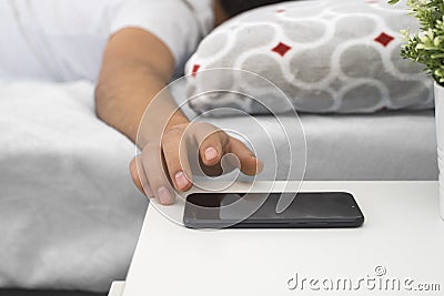 Young man sleeping in his bed with his cell phone on the nightstand, Stock Photo