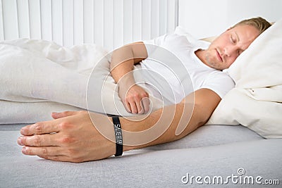 Young man sleeping wearing smart wristband Stock Photo
