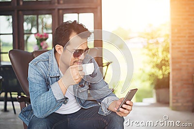 Young man with smartphone smiling relaxing at cafe. Stock Photo