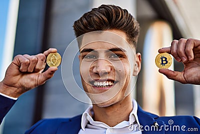 Young man smiling confident holding bitcoin and ethereum at street Editorial Stock Photo