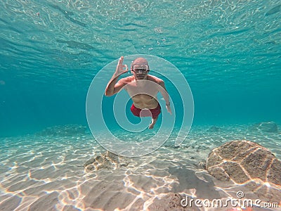 Young man snorkeling in crystal clear waters Stock Photo