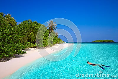 Young man snorkling in tropical island with sandy beach Stock Photo