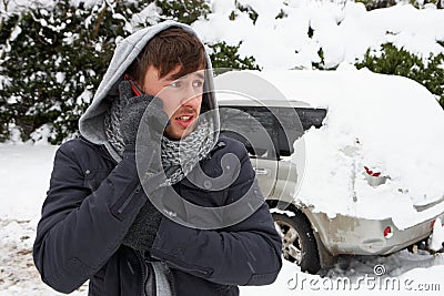 Young man in snow with broken down car Stock Photo