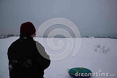 Young man on a snowy hill with inflatable snow tube Stock Photo