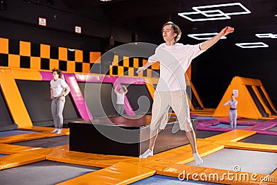 Young man in sport clothes high jumping in trampoline arena Stock Photo