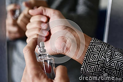 Young man spraying perfume on his wrists Stock Photo