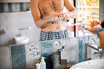 Young man spraying shaving foam on hand Stock Photo