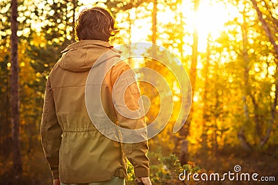 Young Man standing alone in forest outdoor with sunset nature on background Stock Photo