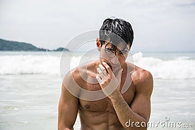 Young man standing on beach by the ocean Stock Photo