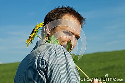 Young man standing with a sunflower Stock Photo