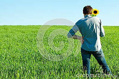 Young man standing with a sunflower Stock Photo