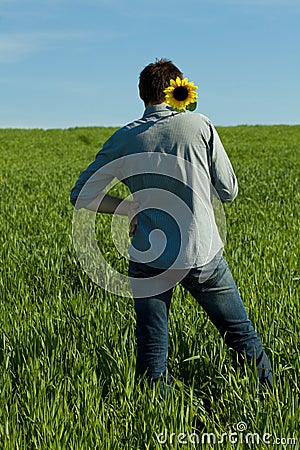 Young man standing with a sunflower Stock Photo