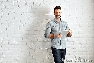 Young man standing at wall using tablet Stock Photo