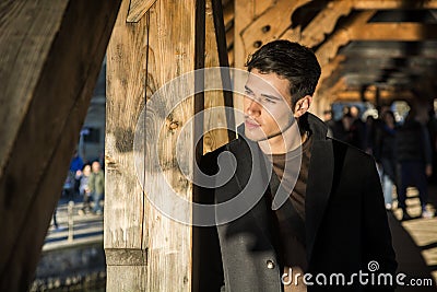 Young man standing on wooden footbridge in Switzerland while looking away Stock Photo