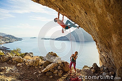Young man starts climbing in cave, his female partner belaying him Stock Photo