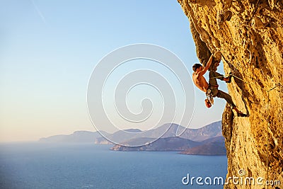 Young man struggling to climb challenging route on cliff Stock Photo