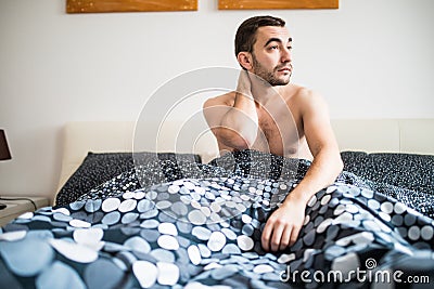 Young man suffering from neckache in bedroom at home Stock Photo