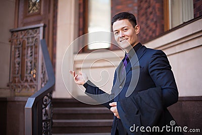 A young man in a suit shows a luxury house for sale. A benevolent realtor Stock Photo
