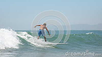 Young man on surfboard sliding on the waves on a clear day Editorial Stock Photo