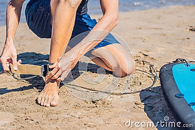 Young man surfer getting on the surfboard`s leash Stock Photo
