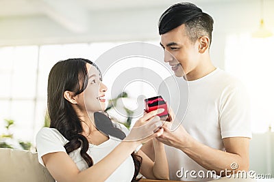 Young man surprises his girlfriend with present at home Stock Photo