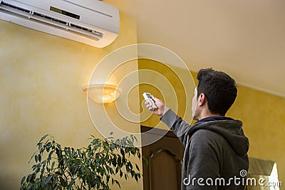 Young man switching on the air conditioner Stock Photo