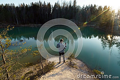Young man take travel photos - Beautiful turquoise lake in Latvia - Meditirenian style colors in Baltic states - Stock Photo