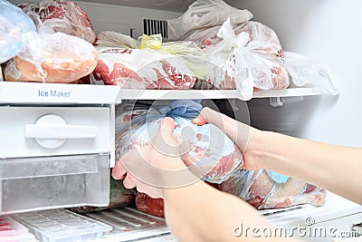 A young man takes out convenience foods from the freezer to prepare dinner in the microwave Stock Photo