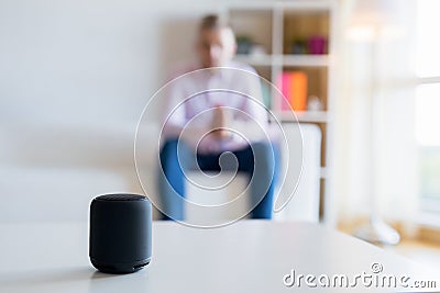 Man talking to virtual assistant smart speaker in living room Stock Photo